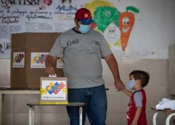 Un hombre junto a su hijo vota en un colegio electoral de Caracas, durante las elecciones regionales de Venezuela, el domingo 21 de noviembre de 2021. Foto: Rayner Peña / EFE.