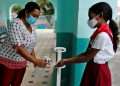 Una maestra desinfecta las manos de una estudiante en una escuela de La Habana, tras la reanudación de las clases presenciales el 8 de noviembre de 2021. Foto: Ernesto Mastrascusa / EFE.