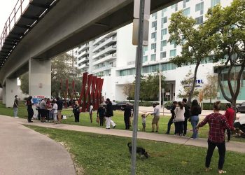 Personas esperan en una fila su turno en un punto de pruebas rápidas de Covid-19 instalado bajo la vía de un tren elevado en el barrio de Brickell en Miami (EEUU), este 27 de diciembre de 2021. Foto: Ana Mengotti/EFE.