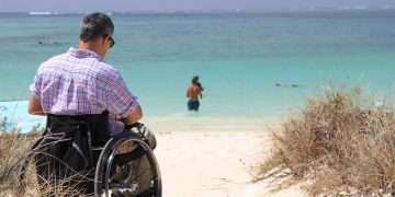 Persona con discapacidad disfruta de una playa como turista. Foto: Organización Mundial de Turismo.