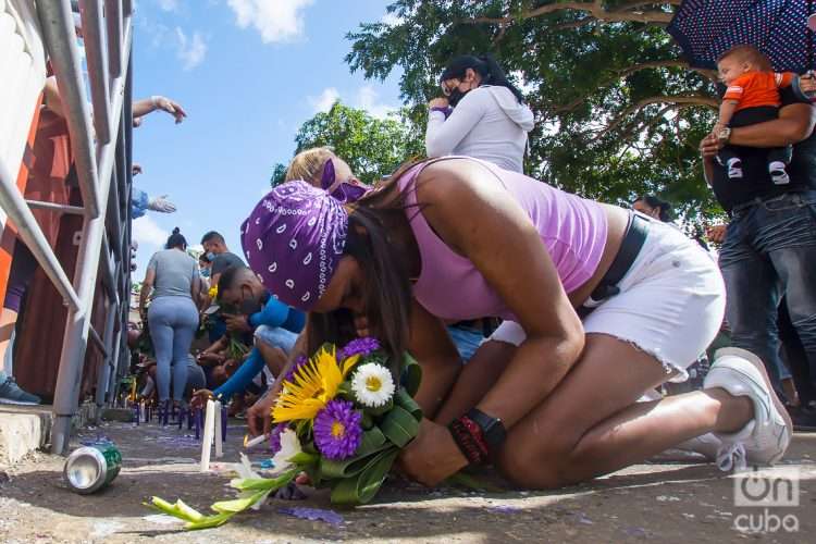 Una mujer se arrodilla con una ofrenda en la mano, pide calladamente, a San Lázaro. Otmaro Rodríguez