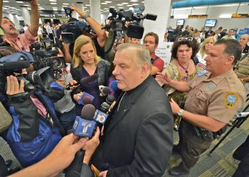 El arzobispo de Miami, Thomas Wenski, presta declaraciones en el aeropuerto de Miami, protegido por la policía local, momentos antes de partir hacia La Habana para asistir a la visita del papa Benedicto XVI a la Isla (2012). Foto: Rui Ferreira