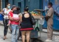 Un hombre con un niño en brazos compra productos agrícolas a un vendedor particular en La Habana. Foto: Otmaro Rodríguez.