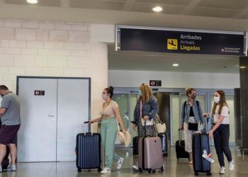 Turistas con nasobucos llegan al aeropuerto de Menorca en un vuelo procedente de Londres. Foto: EFE.