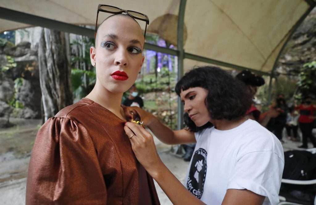 La diseñadora cubana Loypa Izaguirre (d) ajusta la ropa de su colección a una modelo durante un desfile de moda en La Habana. Foto: Ernesto Mastrascusa / EFE.