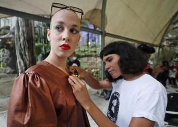 La diseñadora cubana Loypa Izaguirre (d) ajusta la ropa de su colección a una modelo durante un desfile de moda en La Habana. Foto: Ernesto Mastrascusa / EFE.