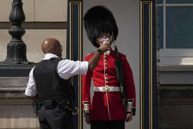 Un policía británico refresca a un miembro de la Guardia Real. Foto: Yahoo.