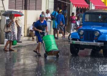 Personas en una calle de La Habana durante una lluvia de verano. Foto: Otmaro Rodríguez.