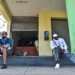 Hombres sentados delante de una bodega, uno de ellos sostiene varias cajetillas de cigarro. Foto: Kaloian.