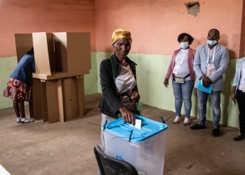 Delegados de los partidos político supervisa el voto de una angolana. | Foto: Lusa
