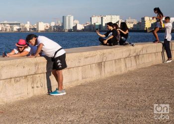 Personass se toman fotos selfie en el malecón de la Habana en 2022 Ciudad al fondo, mar. Foto: Jorge Ricardo