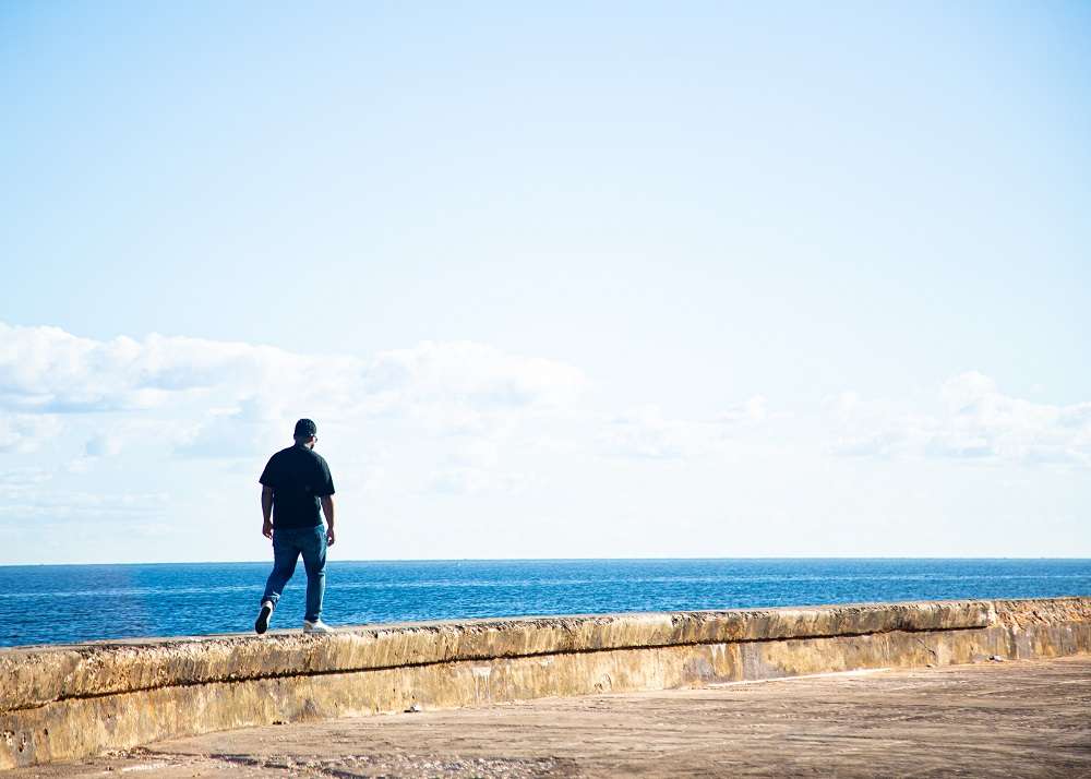 hombre camina sobre el muro del malecon de la habana 