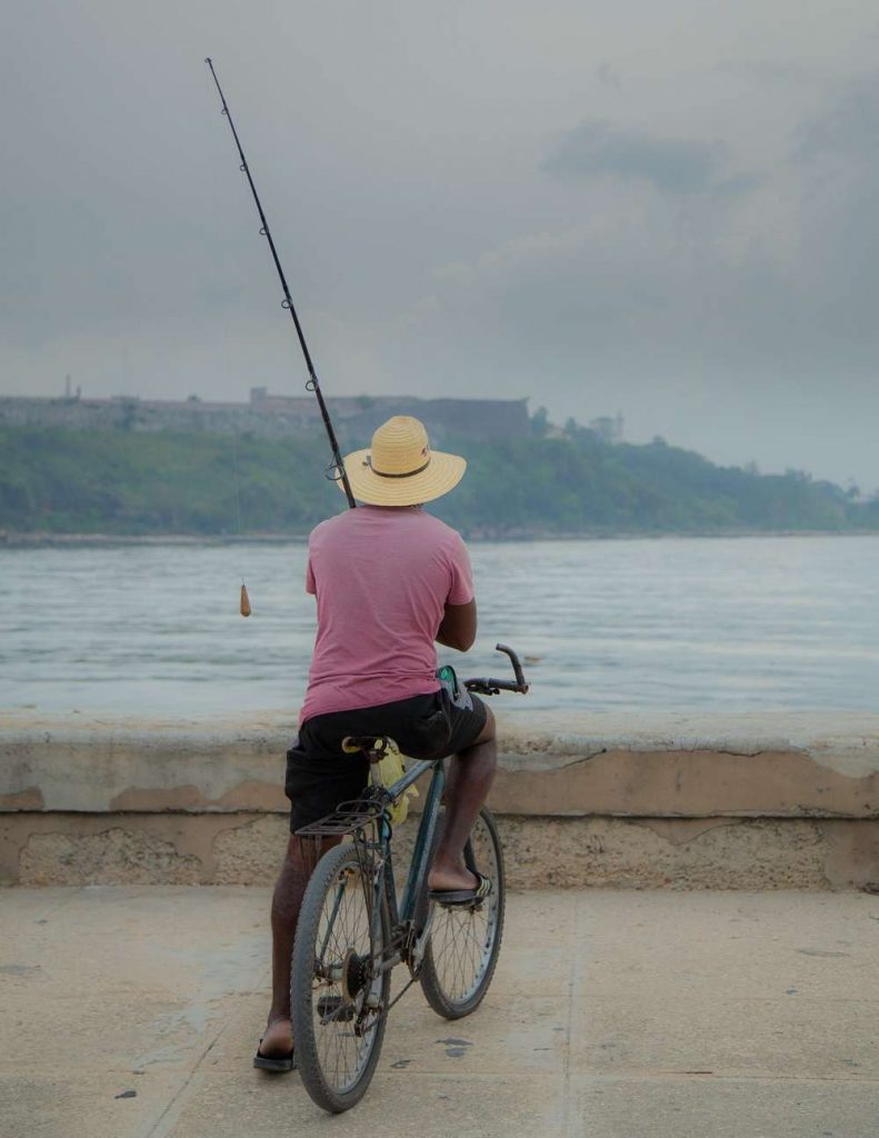 hombre en bicicleta pesca en el malecon de la habana foto jorge ricardo