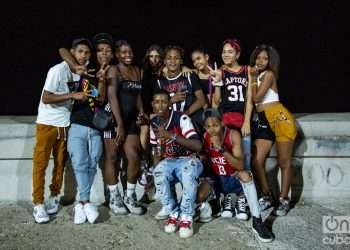 Grupo de adolescentes con camisetas de básquet en el muro del malecón de La Habana de noche Foto Jorge Ricardo.