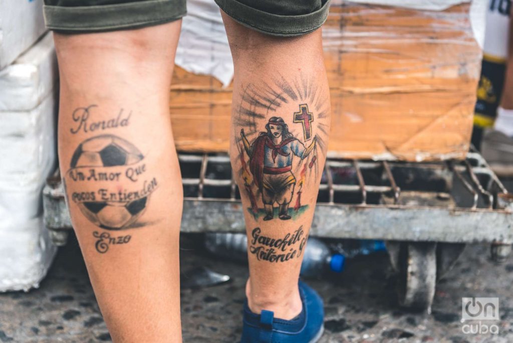 Tatuajes sagrados: En una pierna una pelota de fútbol y en la otra El Gauchito Gil es una figura religiosa,​ objeto de devoción popular en la Argentina.  
