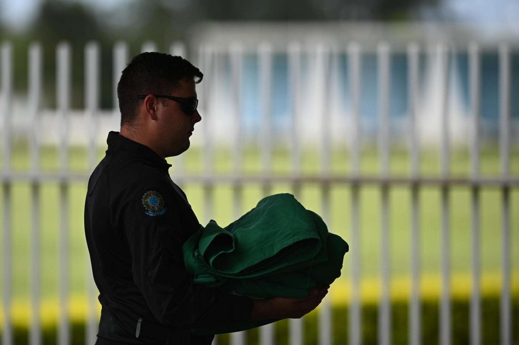 Guardias de seguridad retiran las banderas hoy, 30 de diciembre, frente a la residencia oficial del Palacio de la Alvorada, en Brasilia. Foto: EFE/ Andre Borges.