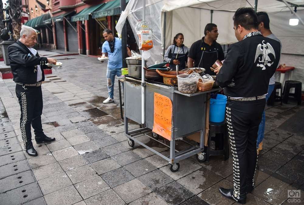 Dos mariachis comen unos tacos en un puesto callejero en Plaza Garibaldi antes de arrancar la jornada. Foto: Kaloian.