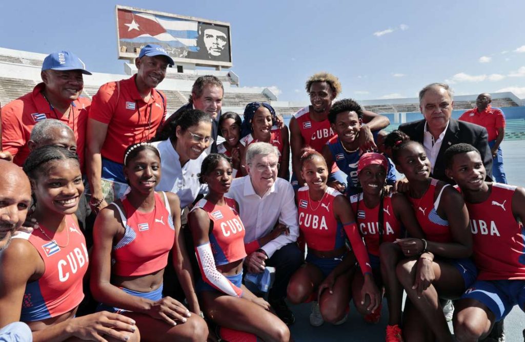 El presidente del Comité Olímpico Internacional (COI), el alemán Thomas Bach (c), posa con atletas cubanos en el Estadio Panamericano de La Habana, el 3 de marzo de 2023. Foto: Ernesto Mastrascusa / EFE.