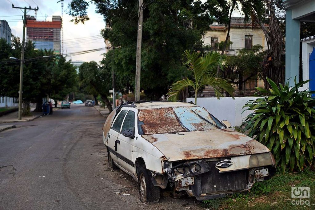 Ningún estado de deterioro es suficiente para deshacerse del vehículo. Al fondo, la Torre K en construcción, próximamente el edificio más alto de la ciudad. La Habana, 2023. Foto: Alejandro Ernesto.