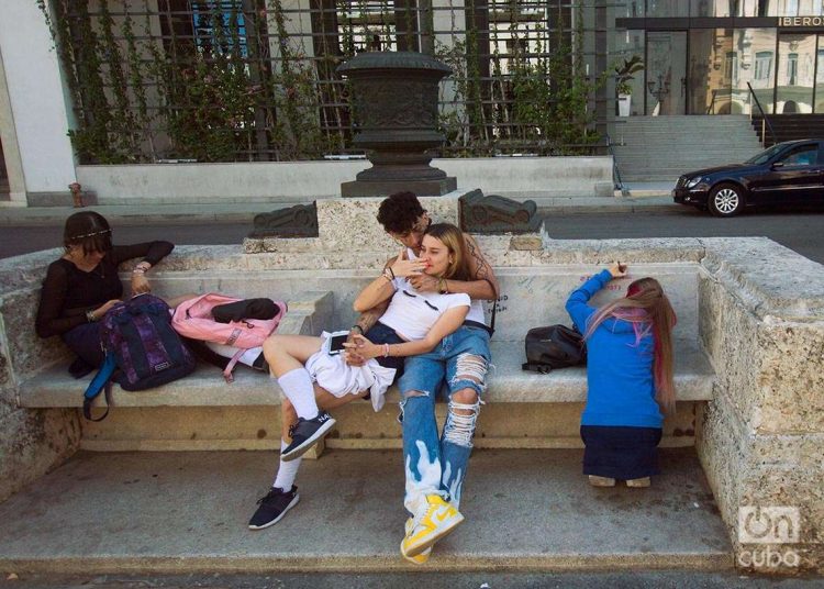 Una joven escribe sobre el mármol de un banco del Paseo del Prado, junto a otros jóvenes. Foto: Otmaro Rodríguez.