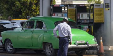 Un policía (de espaldas) observa a un coche antiguo en una gasolinera, en La Habana. Foto: Yander Zamora / EFE / Archivo.