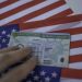 Permanent Resident Green card  of United states of America on flag of USA. Foto: www.telemundo.com