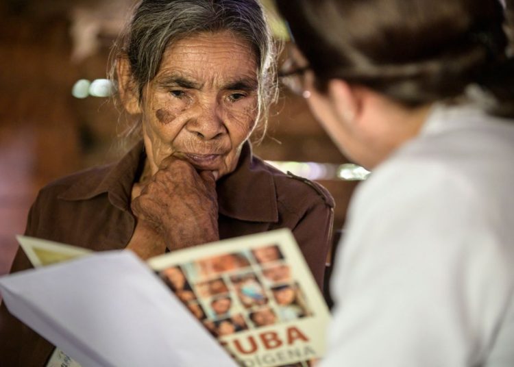 Proyecto Cuba Indígena. Catalina Pileta del Toro, en su casa de Virgina Pecuaria, recibe los resultados de su análisis de ADN de manos de la doctora Beatriz Marcheco, Felicidad de Yateras, Guantánamo, Cuba. Foto: cortesía de Héctor Garrido.