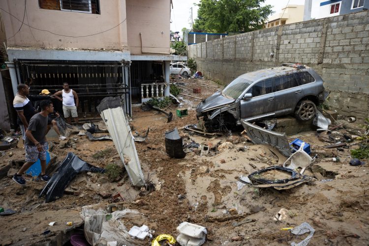 Un hombre recupera pertenencias junto a varios vehículos que fueron arrastrados por la corriente, en Santo Domingo. Foto: Orlando Barría/EFE.