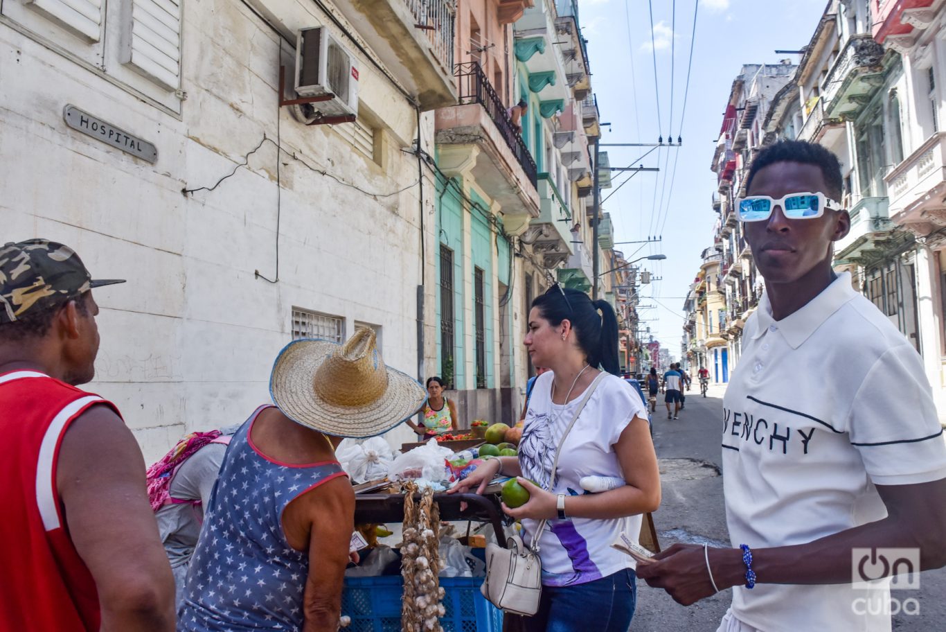 En una calle de Centro Habana, varias personas comprando alimentos a un carretillero. Foto: Kaloian.