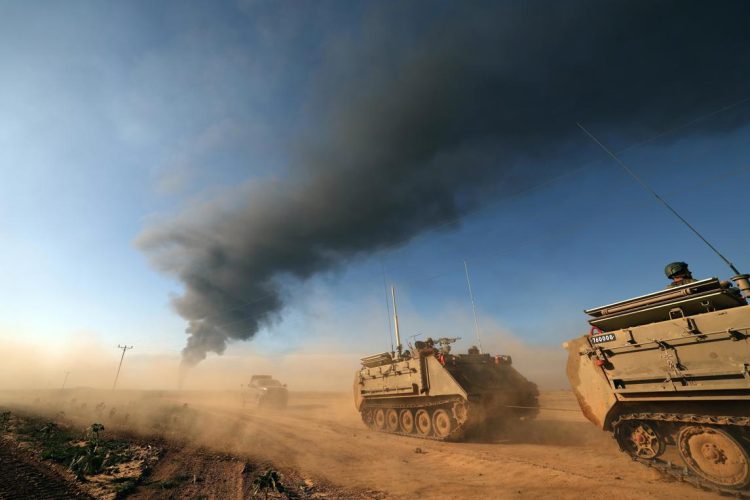 Vehículos blindados israelíes patrullando a lo largo de la parte sur de la frontera con la Franja de Gaza, mientras al fondo se eleva humo desde la zona cercana a Khan Yunis, el 21 de enero de 2024. Foto: Atef Safadi / EFE.