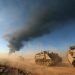 Vehículos blindados israelíes patrullando a lo largo de la parte sur de la frontera con la Franja de Gaza, mientras al fondo se eleva humo desde la zona cercana a Khan Yunis, el 21 de enero de 2024. Foto: Atef Safadi / EFE.