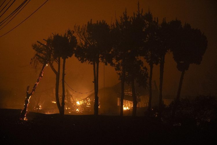 Fotografía de una casa en llamas por un incendio que comenzó en la reserva natural del lago Peñuelas y ha llegado hasta las zonas urbanas hoy, en Viña del Mar (Chile). El primer gran incendio forestal de la temporada estival en los alrededores de la ciudades costeras de Valparaíso y Viña del Mar obligó este viernes a evacuar varias comunas del interior, amenaza aún con llegar a ambas localidades y ha cubierto de denso humo negro toda la costa, llegando incluso a playas más lejanas como Concón, Quintero y Maitencillo, situadas a casi un centenar de kilómetros del epicentro de la catástrofe. EFE/ Adriana Thomasa