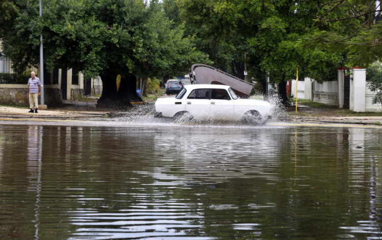 Fotografía de un auto que cruza por una calle anegada por las fuertes lluvias este sábado en La Habana (Cuba). Las intensas lluvias que afectan la región occidental de Cuba desde el viernes han dejado 270.000 clientes sin servicio eléctrico, 26 derrumbes totales sólo en La Habana y unas 762 personas autoevacuadas en casas de familiares, informaron este sábado las autoridades del país caribeño. EFE/ Ernesto Mastrascusa