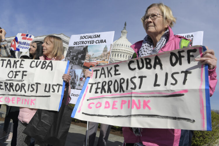 La activista Medea Benjamín (i), del grupo Code Pink, y otra miembro de esa organización, sostienen unas pancartas contra la inclusión de Cuba en la lista de países patrocinadores del terrorismo, mientras interrumpen a la congresista republicana por Florida, María Elvira Salazar, durante una rueda de prensa celebrada este viernes frente al Congreso en Washington. Foto: Lenin Nolly / EFE.