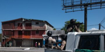 Policías patrullan una calle cercana a la comisaría de Carrefour Aéroport, que fue incendiada por miembros de pandillas en Puerto Príncipe. Foto: Johnson Sabin / EFE.