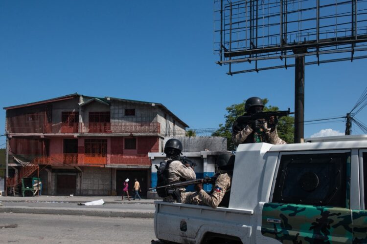 Policías patrullan una calle cercana a la comisaría de Carrefour Aéroport, que fue incendiada por miembros de pandillas en Puerto Príncipe. Foto: Johnson Sabin / EFE.