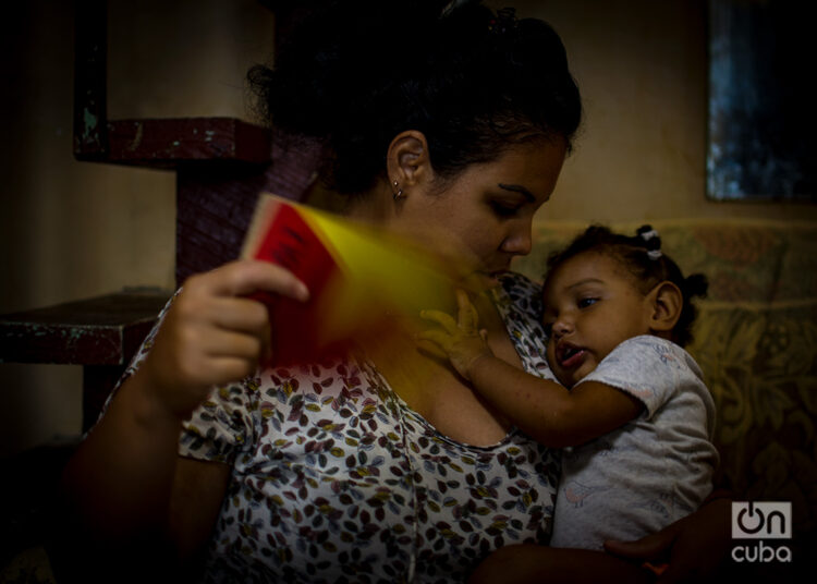 Una madre echa aire a su hija durante un apagón en Cuba. Foto: Otmaro Rodríguez / Archivo.