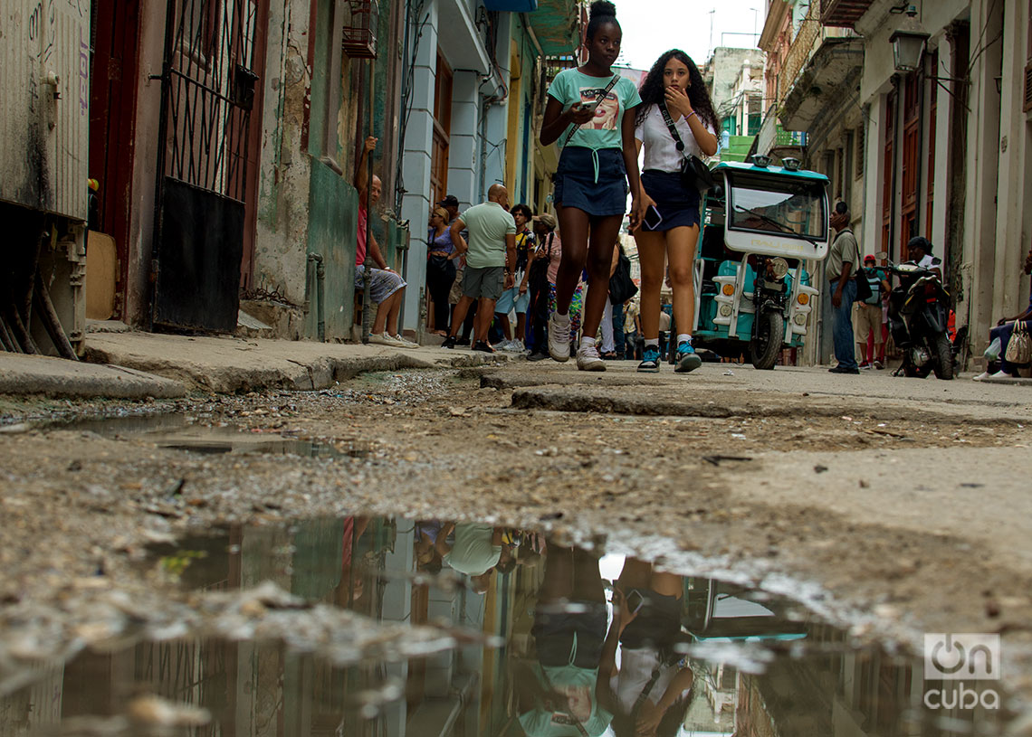 Dos jóvenes caminan por el medio de una calle en La Habana. Foto: Otmaro Rodríguez.