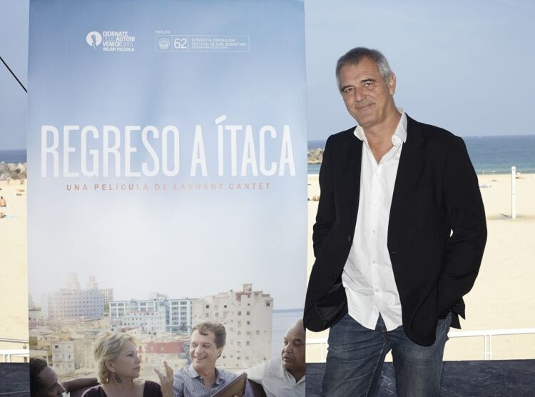 El cineasta francés Laurent, fallecido el 24 de abril de 2024, junto a un afiche de su filme “Regreso a Ítaca”. Foto: elasombrario.publico.es / Archivo.