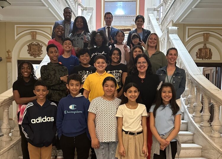 Niños de la escuela primaria Harriet Tubman, en Washington, posan en una foto junto a personal de la embajada de Cuba en Estados Unidos. Foto: Prensa Latina.