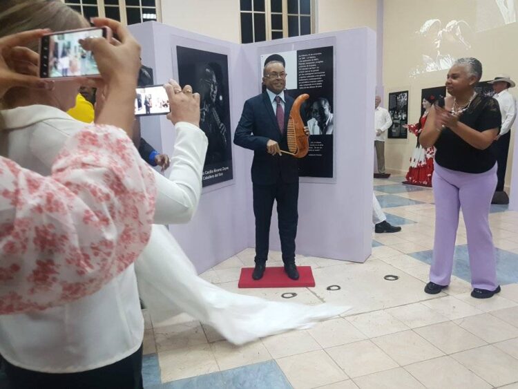 La escultura en cera policromada, muestra al “Caballero del Son” de pie, vestido con un traje azul oscuro y un güiro en la mano, instrumento que lo identificaba en los conciertos. Foto: Tomada de CMKX Radio Bayamo.