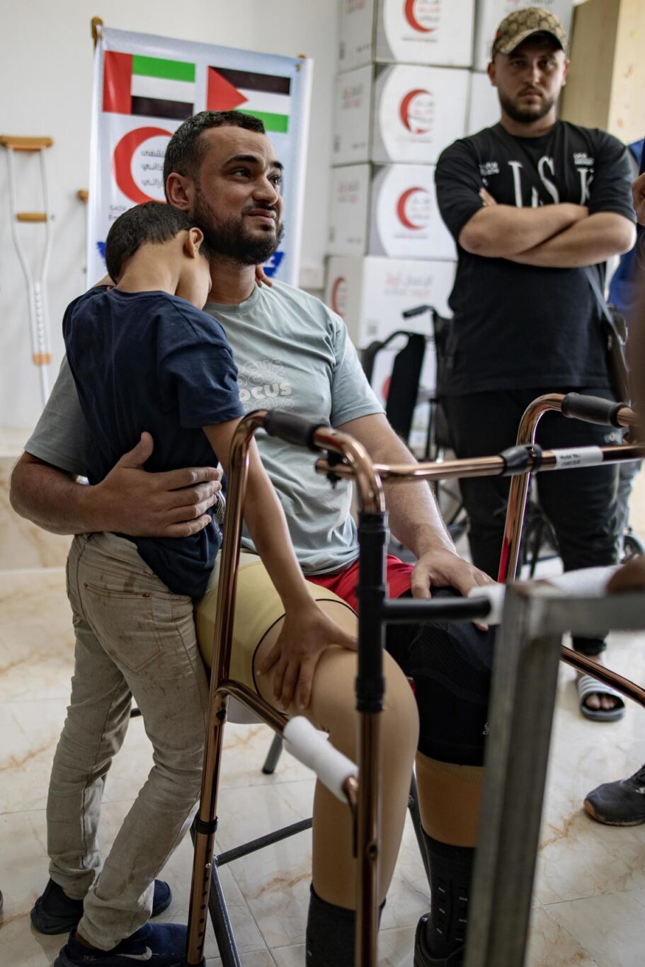 Ahmed Abu Zubaida (C), amputado, abrazado por su hijo después de recibir una prótesis en el Hospital emiratí de Rafah, Gaza, el 5 de mayo de 2024. Foto: EFE/EPA/Haitham Imad. 