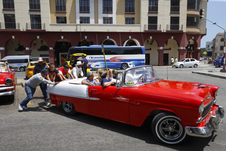 Personas empujan un coche clásico con turistas, en La Habana. Foto: Yander Zamora / EFE / Archivo.