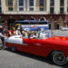 Personas empujan un coche clásico con turistas, en La Habana. Foto: Yander Zamora/EFE.