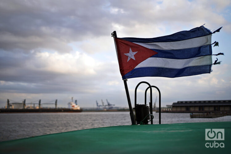 La bandera cubana ondeando en el techo de la añosa y maltrecha lanchita que cien veces al día hace el trayecto entre La Habana, Casablanca y Regla. Foto: Alejandro Ernesto.