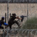 Migrantes ilegales intentan cruzar por una barricada de alambre con púas en las inmediaciones de la frontera con Estados Unidos y México. Foto: Luis Torres / EFE.