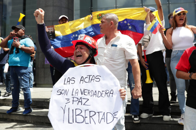 Una mujer sostiene un cartel durante una protesta contra los resultados oficiales de las elecciones en Venezuela, dados por el CNE, en Caracas. Foto: Ronald Peña R. / EFE.