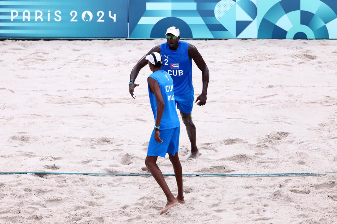 Los cubanos Noslen Díaz (delante) y Jorge Luis Alayo en el partido de voley de playa en el que Cuba derrotó a Estados Unidos, en su estreno olímpico en París 2024. Foto: Anna Szilagyi / EFE.