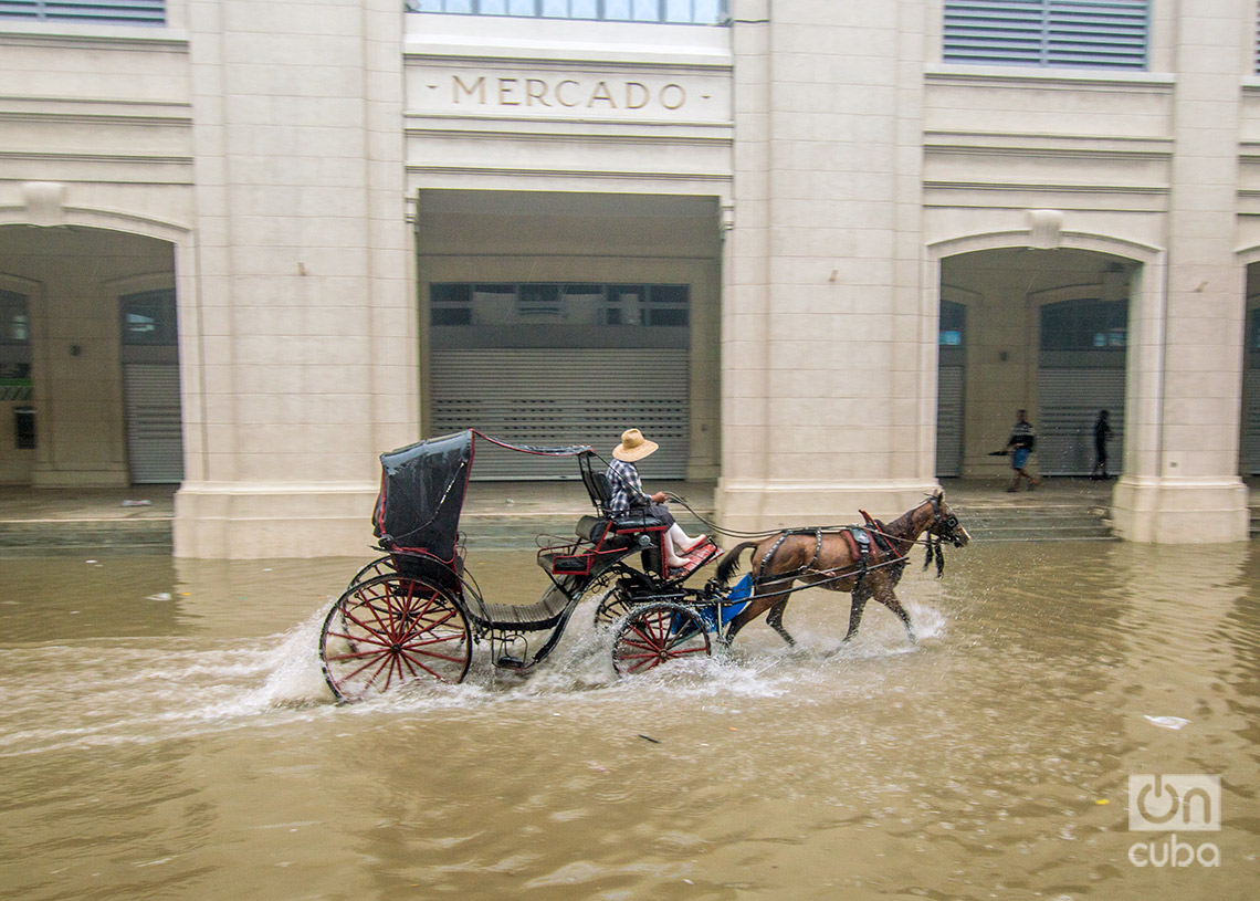 Un coche transita por los alrededores del mercado de Cuatro Caminos, en La Habana, una zona inundada por las lluvias de la tormenta Debby, el 4 de agosto de 2024. Foto: Otmaro Rodríguez.