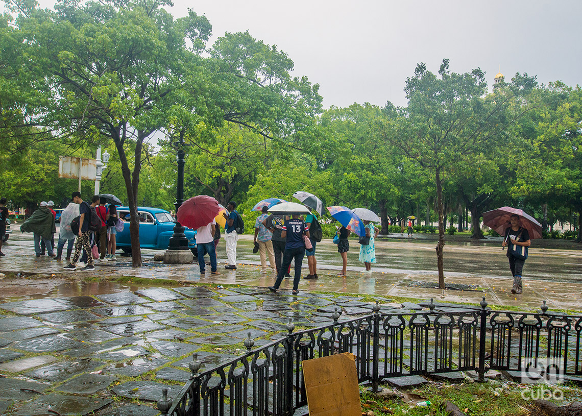 Personas esperan un transporte en el Parque de La Fraternidad, durante las lluvias de la tormenta Debby. Foto: Otmaro Rodríguez.